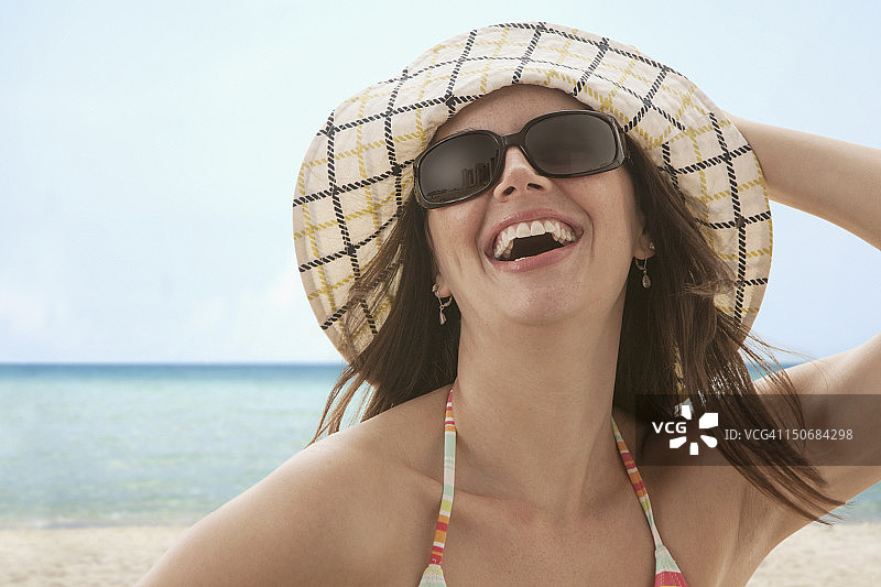 在海滩上戴着帽子的年轻女人图片素材