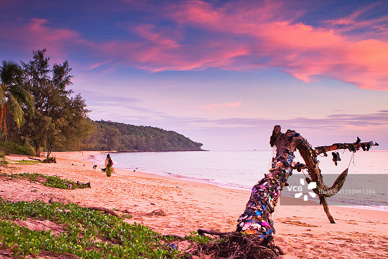 日落时分，沿着水边行走的女人图片素材