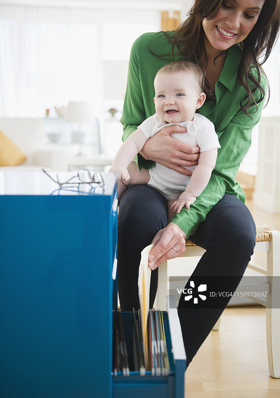 美国新泽西州泽西市，母亲和女婴（6-11个月大）在家办公图片素材