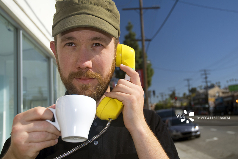男人在公用电话旁喝咖啡图片素材