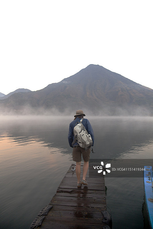 独自走在雾气缭绕的湖边码头上的女人图片素材