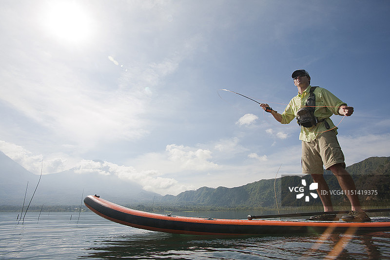 日出时分，男子在雾气蒙蒙的湖面上用iSUP玩飞蝇钓图片素材