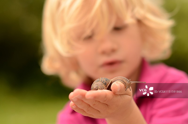 手握蜗牛的男孩图片素材