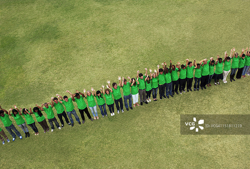 穿着绿色T恤，在田野里举起双臂的人们肖像图片素材