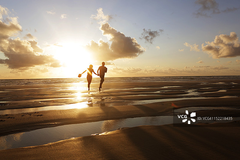 日落时在海滩跑步的情侣图片素材