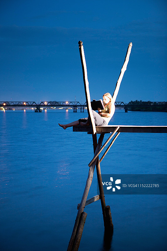 坐在河边平台上阅读的女人图片素材