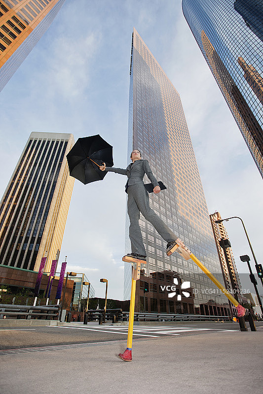 在城市环境中踩高跷的白人女商人图片素材