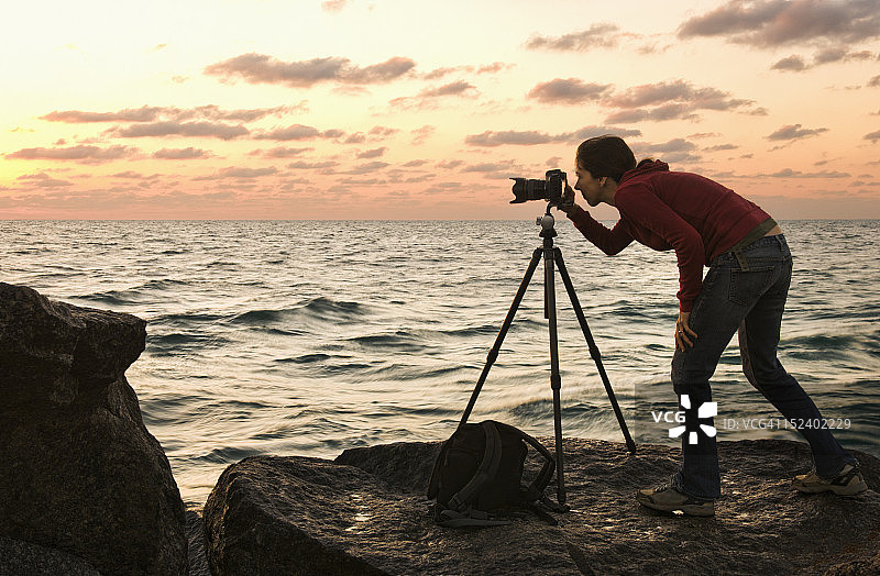 在海边使用相机的混血女人图片素材