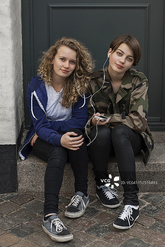 两个女孩拿着iPhone对着镜头微笑图片素材