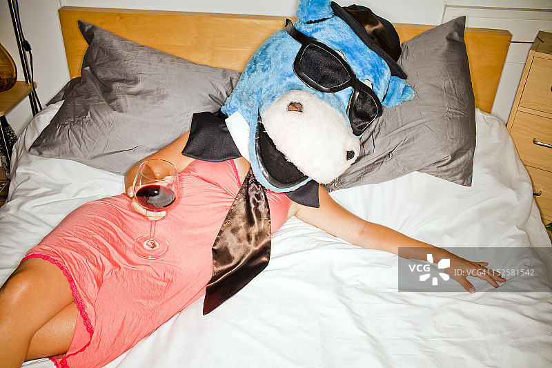 女士躺在床上，戴着假牛头图片素材