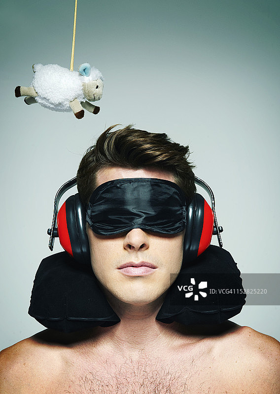 男子戴着睡眠眼罩试图与绵羊睡觉图片素材