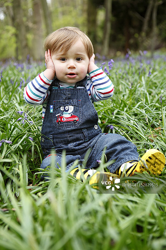 在草地上捂住耳朵的男孩图片素材