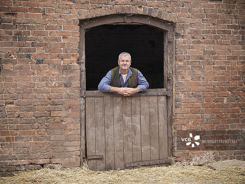 农场主倚靠马厩门的肖像图片素材