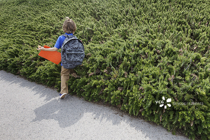 男孩在户外灌木丛旁行走图片素材