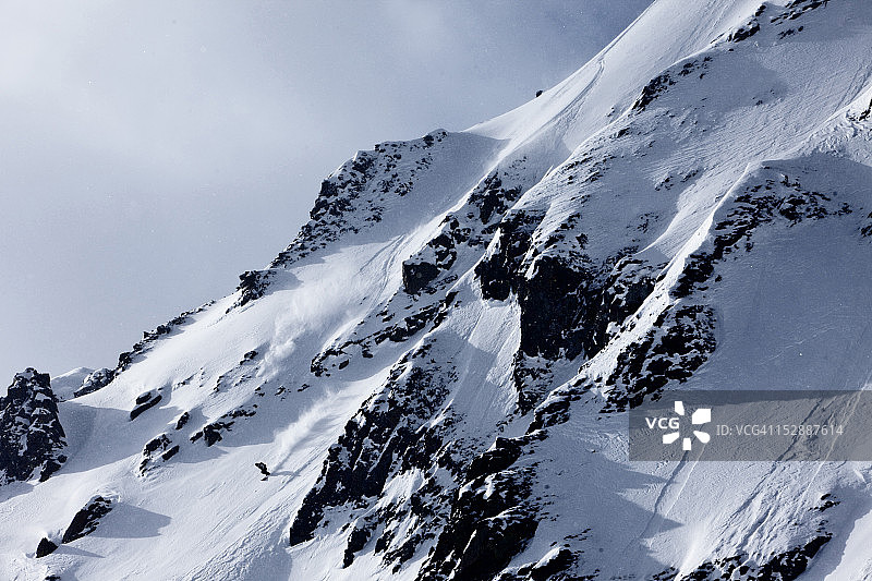 在蒙大拿州阳光明媚的冬日里，在裸露的大山上滑雪的健壮男子图片素材