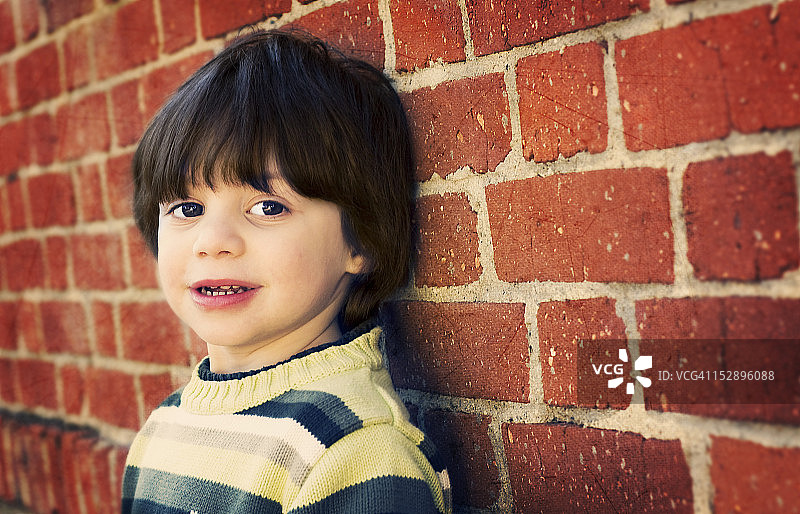 靠在红砖墙上的孩子图片素材
