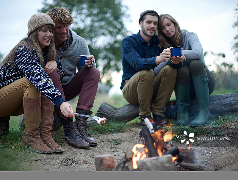 豪华露营者围坐在篝火旁饮酒图片素材