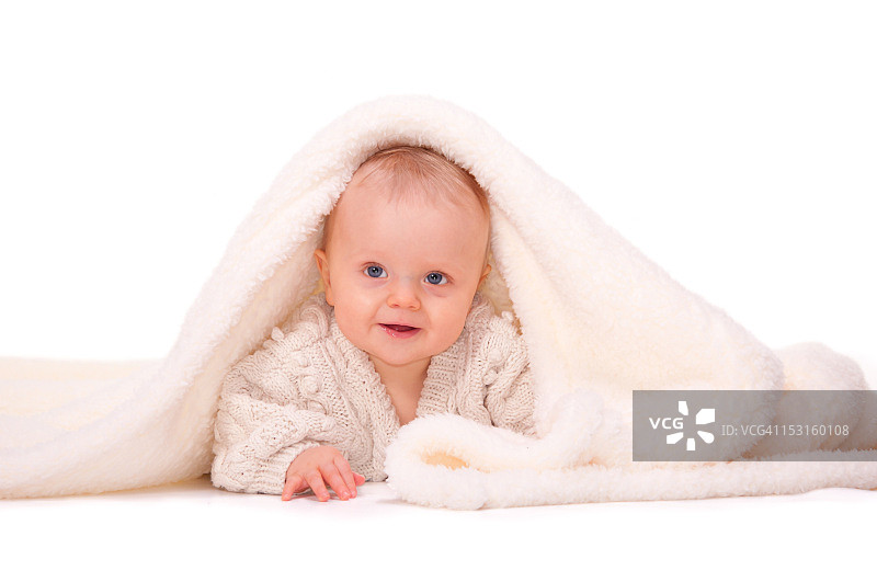 躲在羊皮毯下露出笑脸的可爱宝宝图片素材
