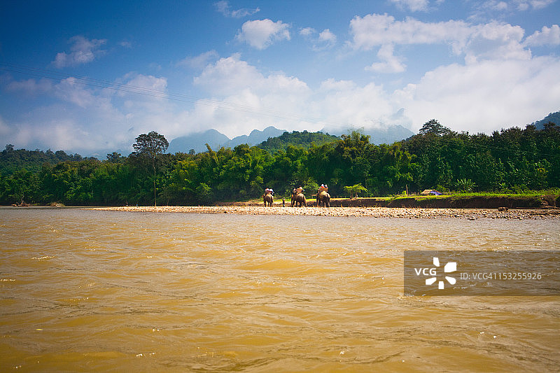 乘坐大象过河的旅行者图片素材