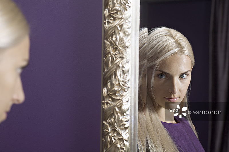 美丽的年轻女人凝视着镜子中的自己图片素材