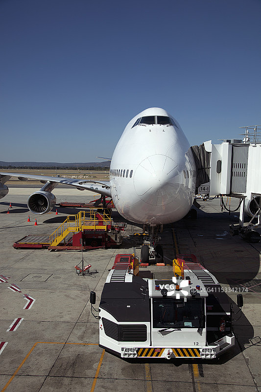 连接廊桥的大型喷气式飞机，前方有拖车图片素材