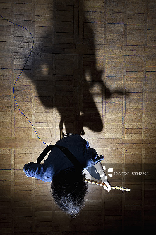 聚光灯下坐在舞台上的吉他手图片素材