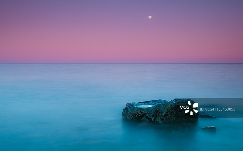 海岸边冉冉升起的月亮与岩石图片素材