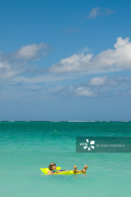 年长的女人漂浮在碧绿的海洋木筏上图片素材