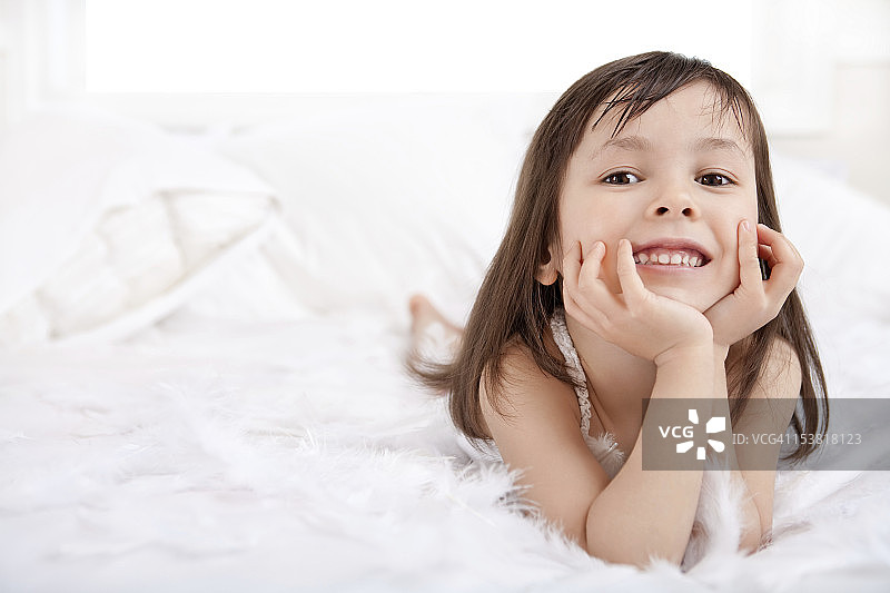 在床上玩羽毛的微笑小女孩图片素材