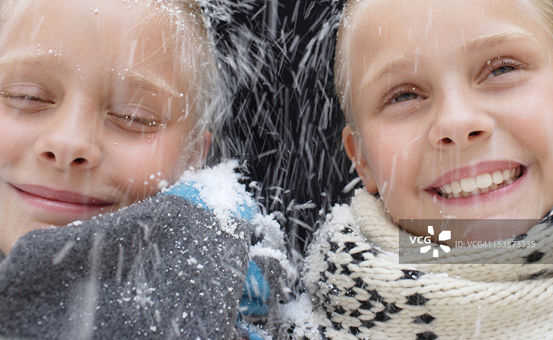 在雪中快乐的年轻双胞胎女孩图片素材