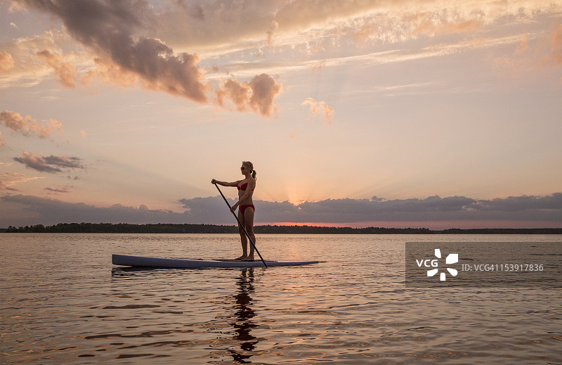 在日落时分玩桨板的女子图片素材