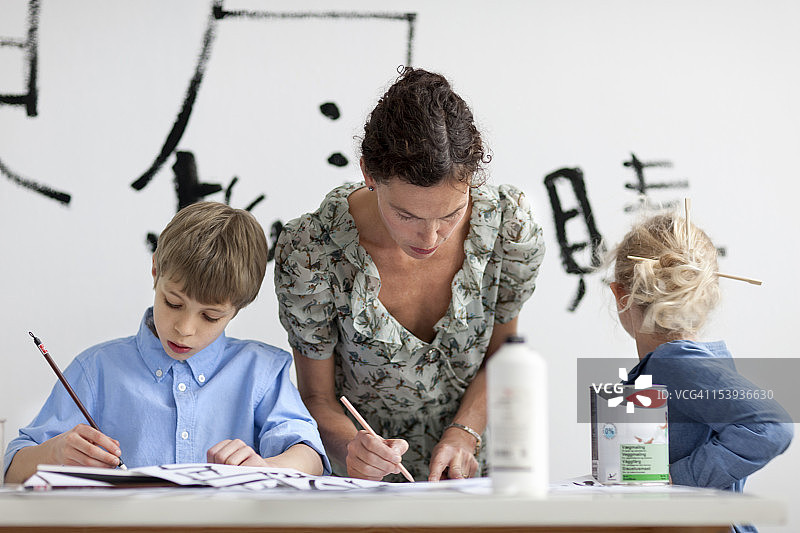 男孩、女孩和女老师一起练习书法图片素材