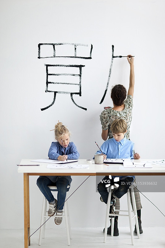 男孩和女孩与女老师一起在美术课上绘画图片素材