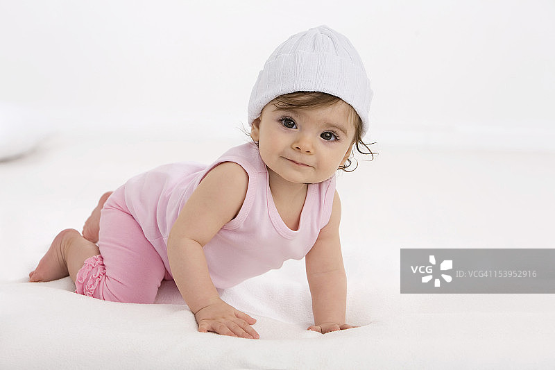 在婴儿毯上爬行，微笑的女婴图片素材