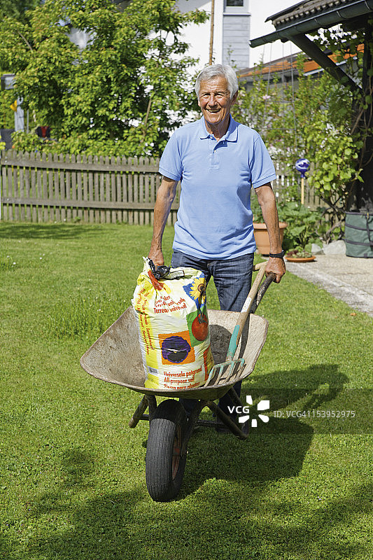 德国巴伐利亚，花园里推独轮车的老年男人图片素材