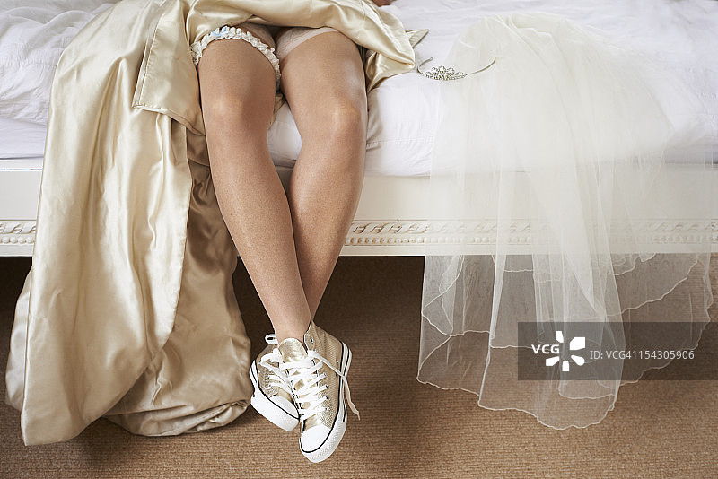 穿着棒球靴的新娘在床上休息图片素材