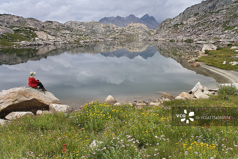 美国怀俄明州布里杰-蒂顿国家森林，徒步者坐在湖边岩石上图片素材
