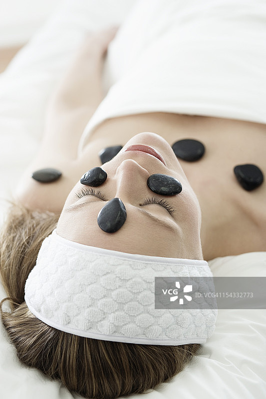 女人在水疗中心接受热石疗法图片素材