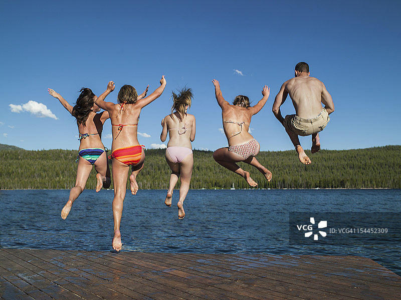朋友们在山地湖泊码头跳跃图片素材