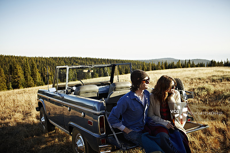 一对年轻夫妇坐在敞篷车的后挡板上图片素材