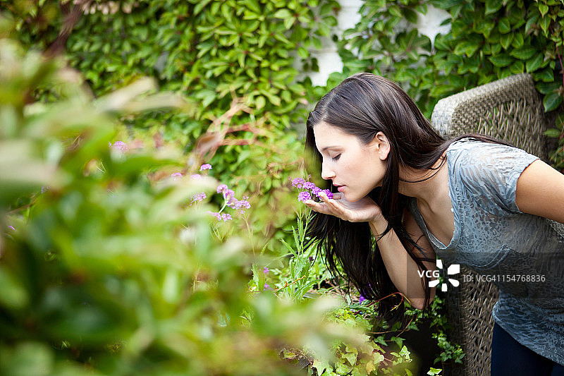 年轻女人在花园里闻花图片素材