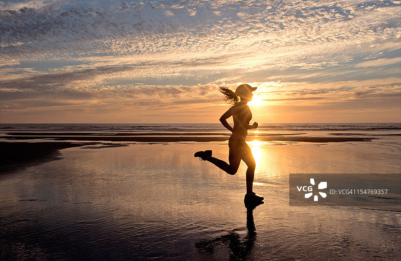 在日出时分的海滩上跑步的女人图片素材
