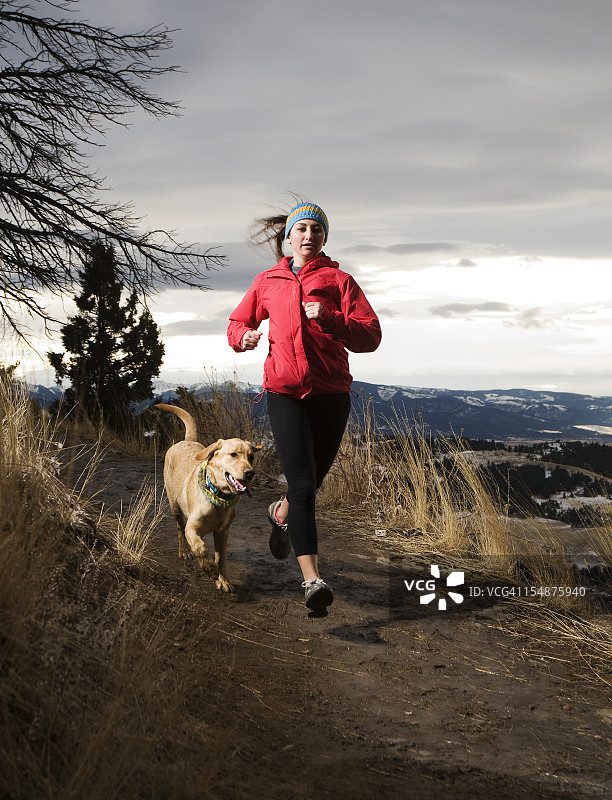 年轻女人和她的狗在山间跑步图片素材
