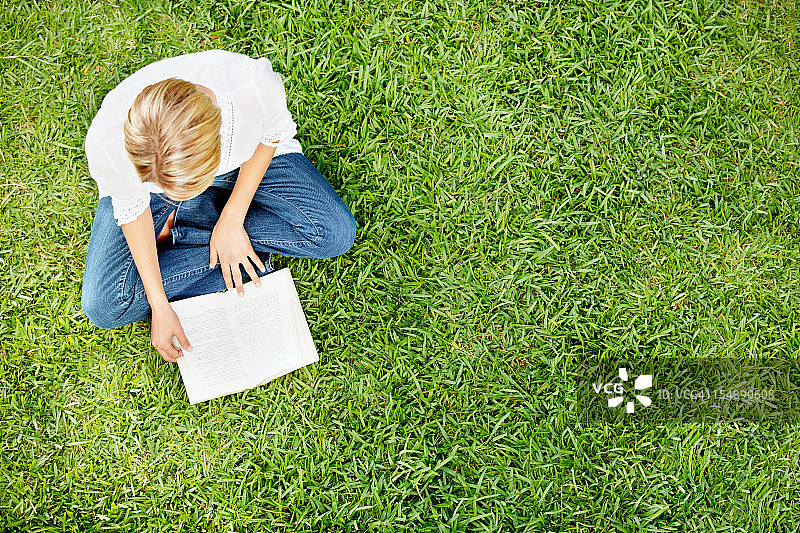 女人坐在绿草地上看书图片素材