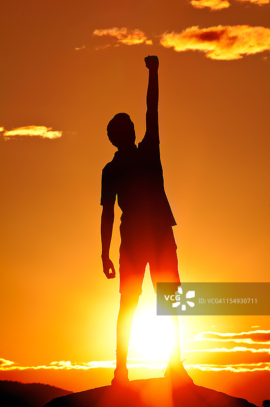 年轻男人在夕阳下挥拳庆祝图片素材
