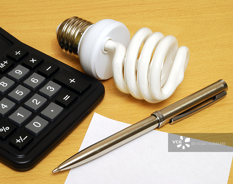 紧凑型荧光灯泡、计算器和笔图片素材