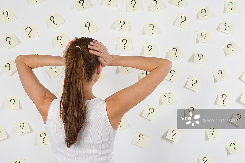 贴满问题的贴纸前的年轻女人图片素材