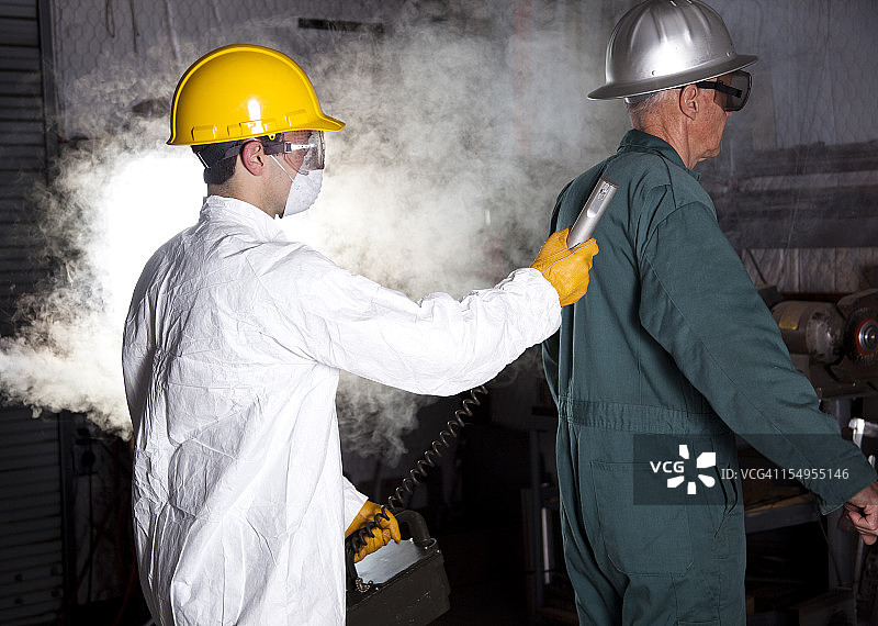 安全检查员使用盖革计数器对工人进行测试图片素材