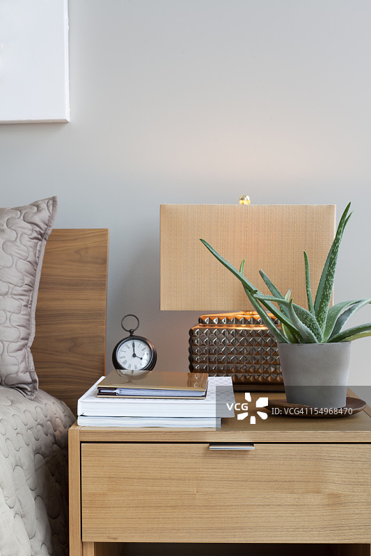 木制床头柜，配有台灯、植物、时钟和纸图片素材