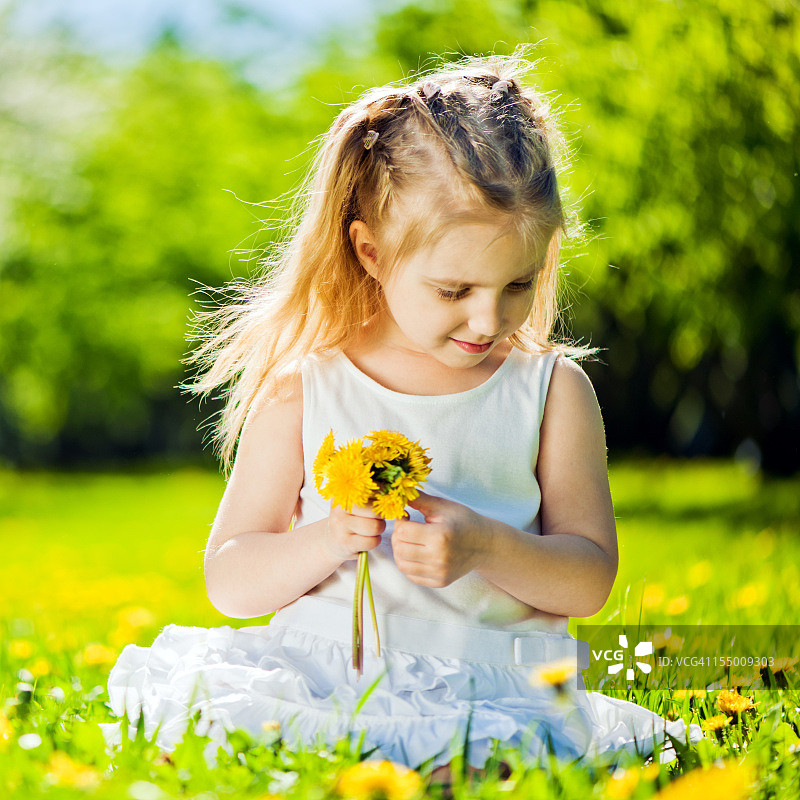 小女孩坐在蒲公英田野上图片素材